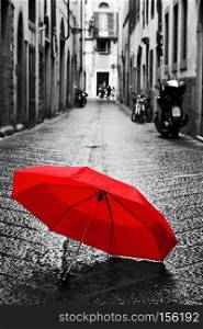Red umbrella on cobblestone street in the old town. Wind, rain, stormy weather. Color in black and white conceptual, idea. Vintage, retro style.. Red umbrella on cobblestone street in the old town. Wind and rain