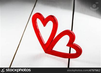 Red Valentine day hearts. Two wooden red painted Valentine day hearts on white wooden background