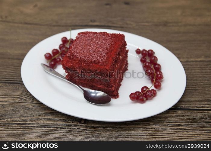 Red Velvet, fresh delicious diet cake with red currant at Dukan Diet on a porcelain plate with a spoon on a wooden background.