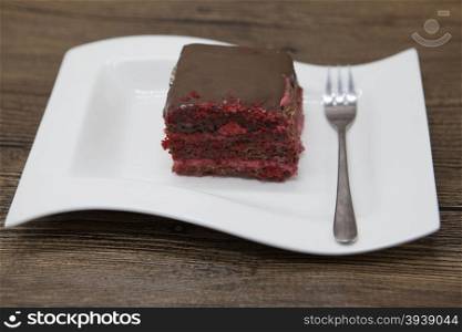 Red Velvet, fresh delicious diet cake with red currant at Dukan Diet on a porcelain plate with a spoon on a wooden background.