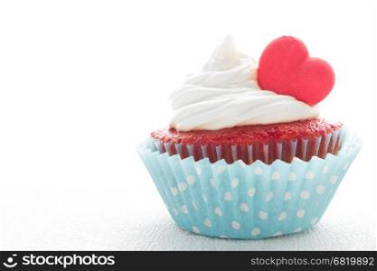 Red velvet heart cupcake with cream cheese frosting and a red heart for Valentine's Day. White background with copy space