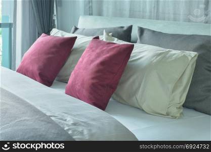 Red velvet pillows with white and gray pillows setting on bed in gray color scheme