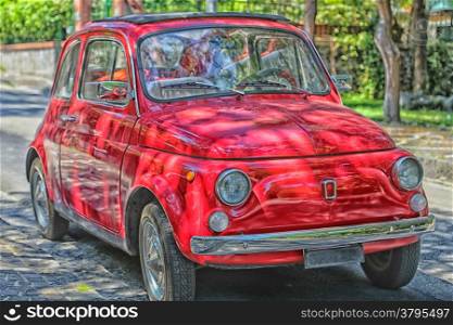 Red vintage Italian runabout car in green park
