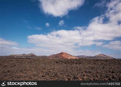 Red volcanic landscape, lava scenary with volcano crater in the background