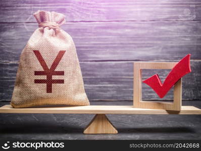 Red vote tick and a chinese yuan or japanese yen money bag on scales. Concept of lobbying for decisions and laws. Estimating cost of making a decision and consequences in the future. Corruption risks.