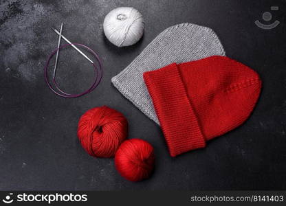 Red warm knitted women’s hat on a concrete background. Hobbies and leisure time. Red warm knitted women’s hat on a concrete background