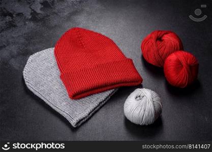 Red warm knitted women’s hat on a concrete background. Hobbies and leisure time. Red warm knitted women’s hat on a concrete background