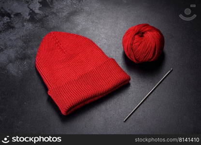 Red warm knitted women’s hat on a concrete background. Hobbies and leisure time. Red warm knitted women’s hat on a concrete background