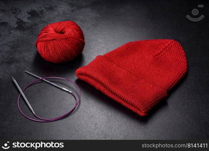 Red warm knitted women’s hat on a concrete background. Hobbies and leisure time. Red warm knitted women’s hat on a concrete background