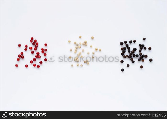 Red, white and black peppercorns on white background.