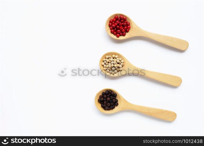 Red, white and black peppercorns with wooden spoon on white background.