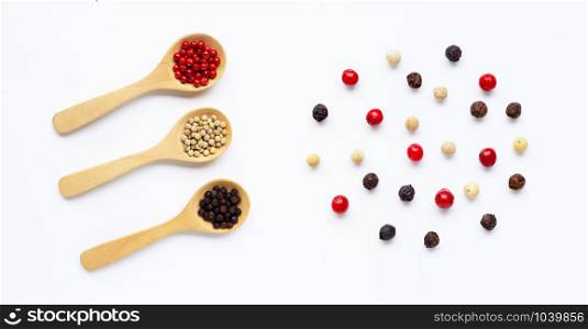 Red, white and black peppercorns with wooden spoon on white background. Top view