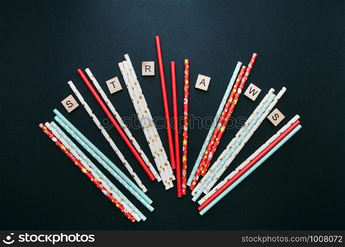 Red, white and blue paper straws and cube letters STRAWS are scattered on a dark background.. Red, white and blue paper straws and cube letters STRAWS are scattered on a dark background