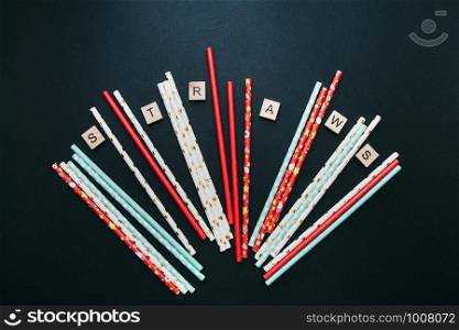 Red, white and blue paper straws and cube letters STRAWS are scattered on a dark background.. Red, white and blue paper straws and cube letters STRAWS are scattered on a dark background
