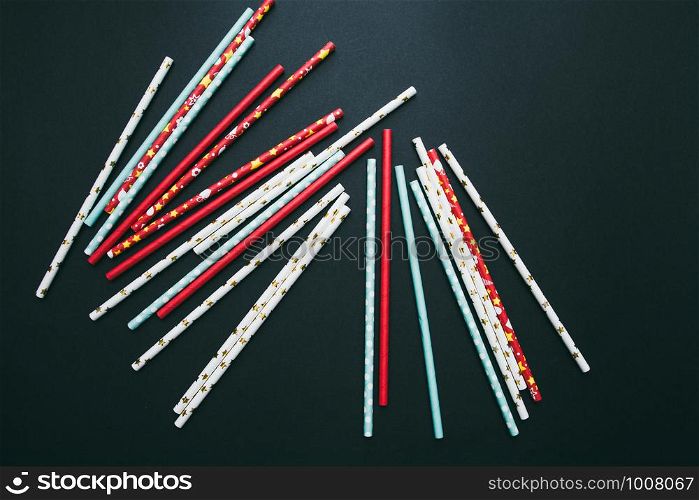 Red, white and blue paper straws are scattered on a dark background.. Red, white and blue paper straws are scattered on a dark background