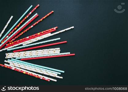 Red, white and blue paper straws are scattered on a dark background.. Red, white and blue paper straws are scattered on a dark background