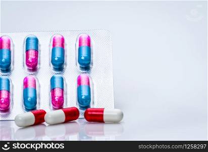 Red-white antibiotic capsule pills and pink-blue anti-fungal granules in capsule pills in blister pack on white background Antibiotics drug resistance and antimicrobial drug use with reasonable.