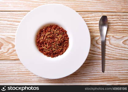 Red wild rice in a white plate over wooden board