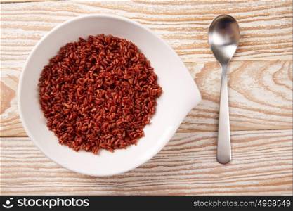 Red wild rice in a white plate over wooden board