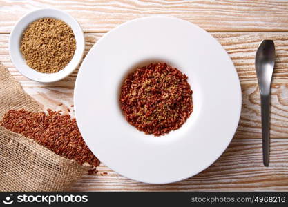 Red wild rice with sesame gomasio seasoning in a white plate over wooden board