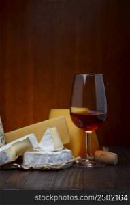 Red wine and cheese assortment on wooden table