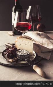 Red wine and cheese plate with fruits and nuts on concrete background. Red wine and cheese plate with fruits and nuts
