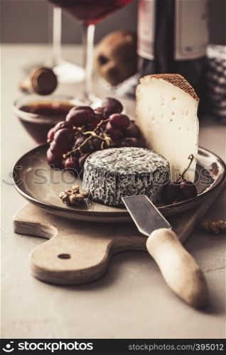 Red wine and cheese plate with fruits and nuts on concrete background. Red wine and cheese plate with fruits and nuts