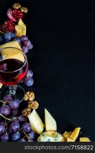 Red wine and snacks arranged in the form of a corner on a black background, with copy-space