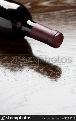 Red Wine Bottle Laying on a Wood Surface Fading Down to White.