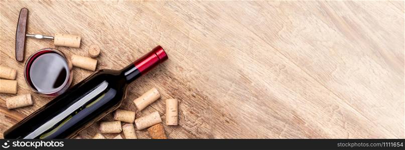 Red wine bottle on wooden table with glass and corks and copy spase