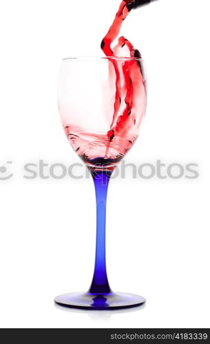 Red wine flowing from a green bottle to a glass. Isolated on white