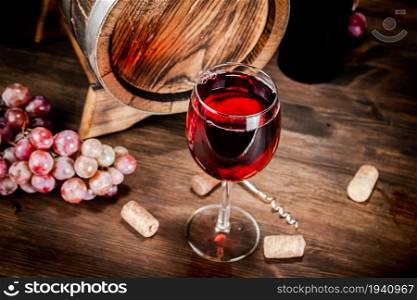 Red wine in a glass and barrel. On a wooden background. . Red wine in a glass and barrel.