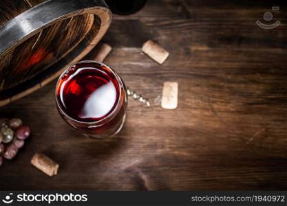Red wine in a glass and barrel. On a wooden background. . Red wine in a glass and barrel.