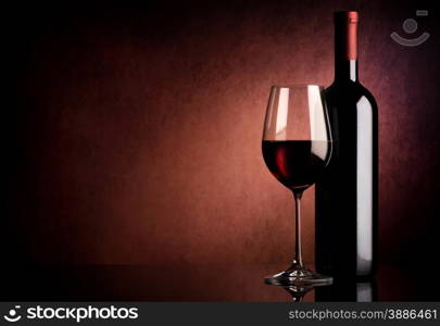 Red wine in bottle and wineglass on vinous background