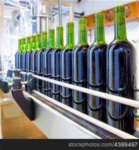 red wine in glass bottling machine at winery
