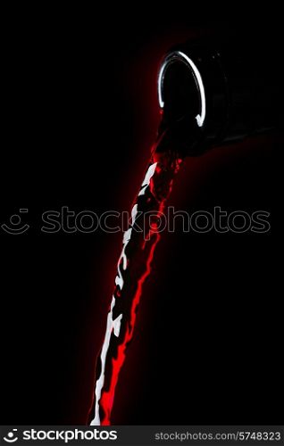 Red wine pouring from bottle isolated on black background. Red wine pouring