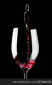 Red wine pouring into glass isolated on black background. Red wine pouring
