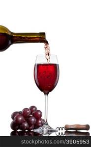 Red wine pouring into glass with grape isolated on white