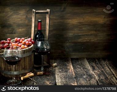 Red wine with a bucket of grapes. On a wooden background.. Red wine with a bucket of grapes.