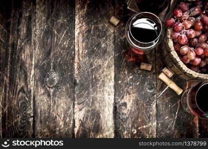 Red wine with a bucket of grapes. On a wooden background.. Red wine with a bucket of grapes.