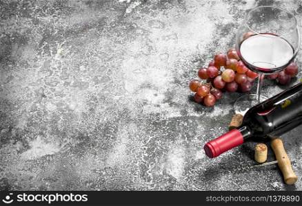 Red wine with a corkscrew. On a rustic background.. Red wine with a corkscrew.