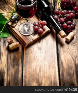 Red wine with a vine branch. On a wooden table.. Red wine with a vine branch.