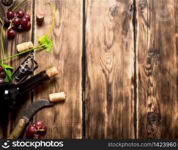 Red wine with a vine branch . On a wooden table.. Red wine with a vine branch .