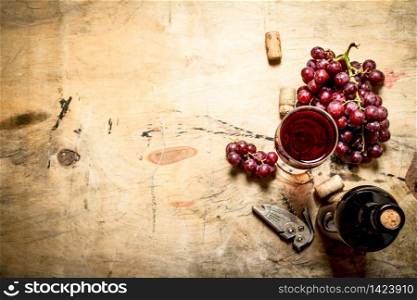 Red wine with grapes and corks. On wooden background.. Red wine with grapes and corks.