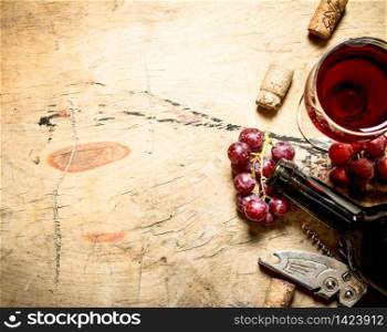 Red wine with grapes and corks. On wooden background.. Red wine with grapes and corks.