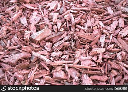 Red wooden chips covering the ground as a decoration. Red wood chips background. Red wood chips mound.