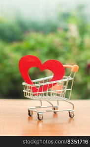 Red wooden heart in the trading cart. concept of buying love. nature background. Health care and purchase of medicines. Health care budget. Love for shopping. Favorite store. Buy love and happiness.