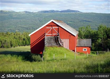 Red wooden house on the slope in Norway