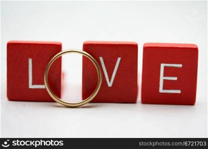 Red wooden letters with a simple yellow gold wedding band.