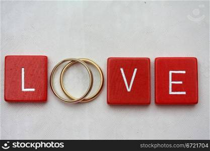 Red wooden letters with simple plain wedding bands.